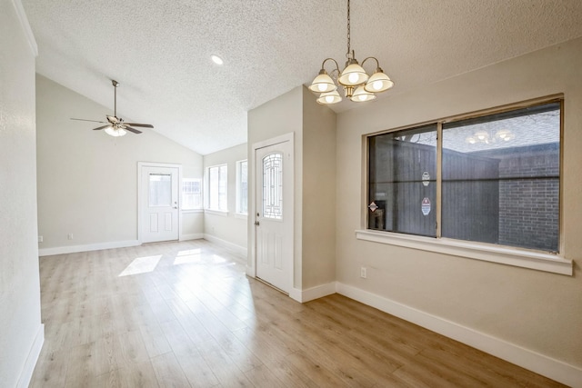 interior space with vaulted ceiling, ceiling fan with notable chandelier, light hardwood / wood-style floors, and a textured ceiling