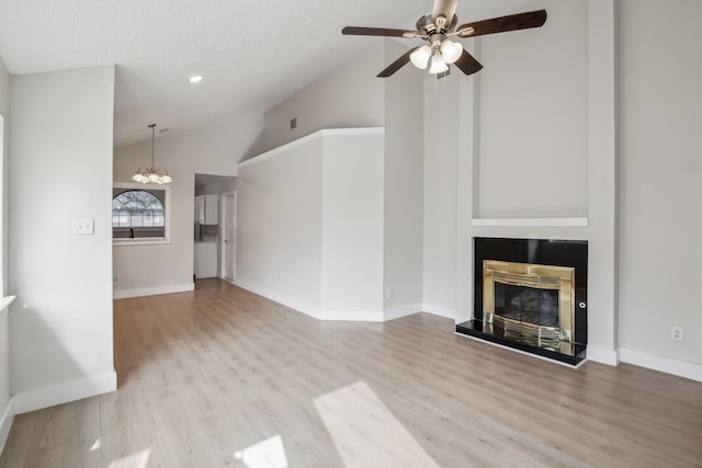 unfurnished living room featuring ceiling fan with notable chandelier, high vaulted ceiling, and light wood-type flooring