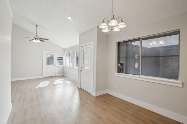 interior space with vaulted ceiling, ceiling fan with notable chandelier, light hardwood / wood-style floors, and a textured ceiling