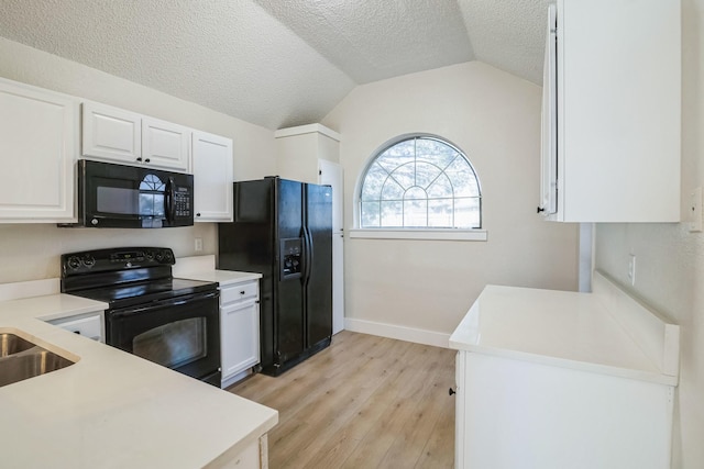 kitchen with white cabinetry, vaulted ceiling, black appliances, and light wood-type flooring