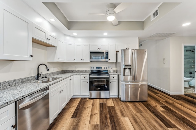 kitchen with light stone countertops, appliances with stainless steel finishes, sink, and white cabinets