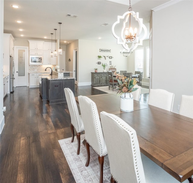 dining room with an inviting chandelier, sink, and dark hardwood / wood-style floors