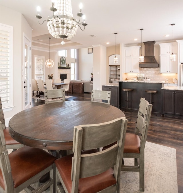 dining room with a chandelier, dark hardwood / wood-style floors, a raised ceiling, and a wealth of natural light