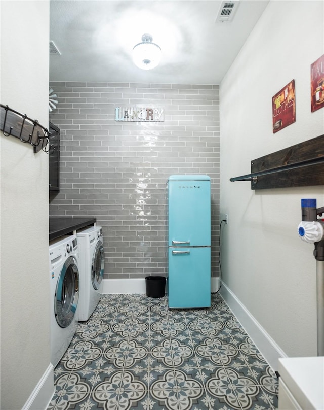 clothes washing area with light tile patterned floors and washing machine and clothes dryer