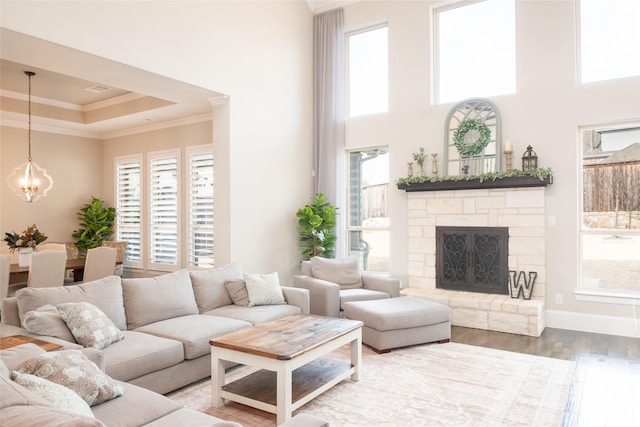 living room with crown molding, a chandelier, a tray ceiling, a fireplace, and hardwood / wood-style floors