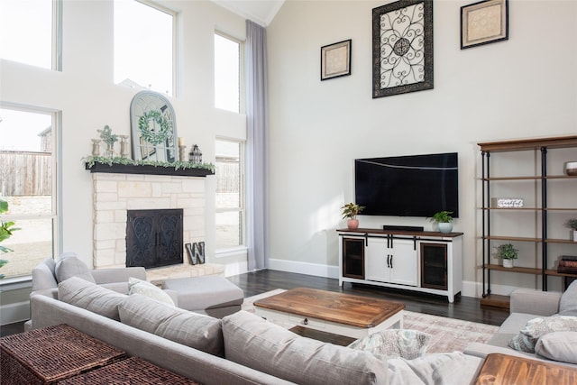 living room with dark hardwood / wood-style flooring, a towering ceiling, and a fireplace