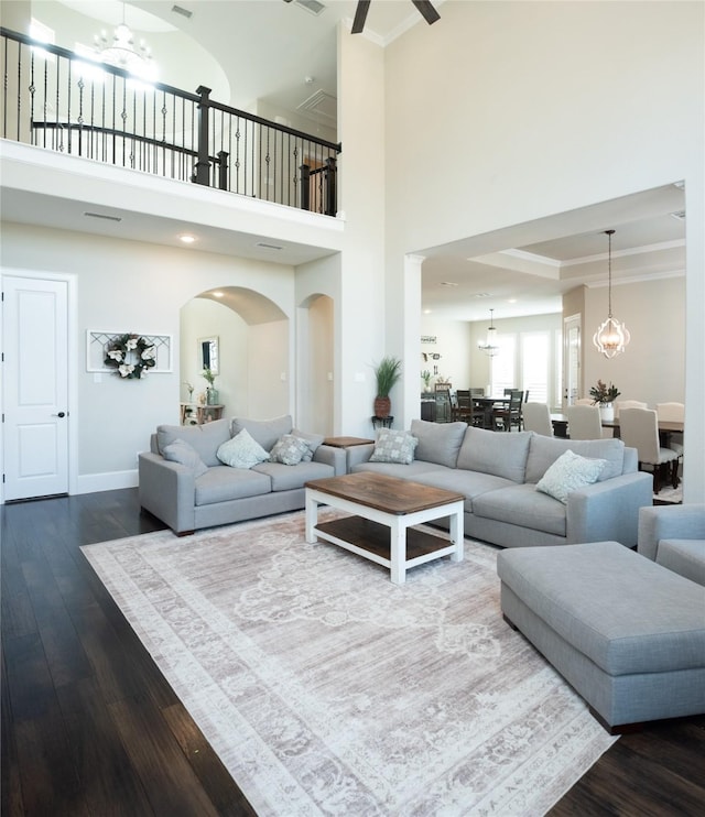 living room with hardwood / wood-style flooring, crown molding, a raised ceiling, and a notable chandelier