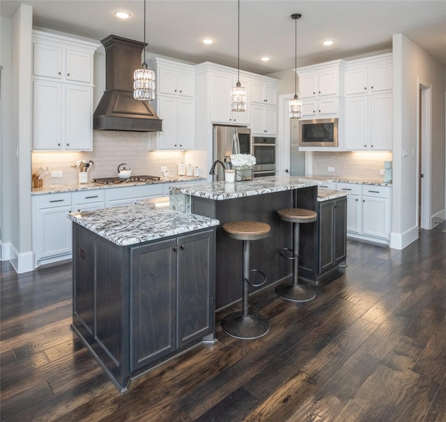 kitchen featuring a large island, hanging light fixtures, white cabinets, and premium range hood