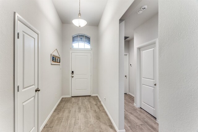 doorway featuring baseboards and light wood-style flooring