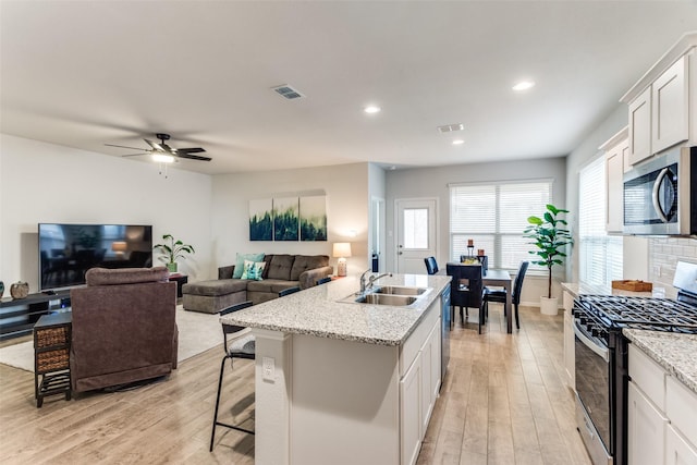 kitchen with stainless steel appliances, visible vents, a sink, and light wood-style flooring