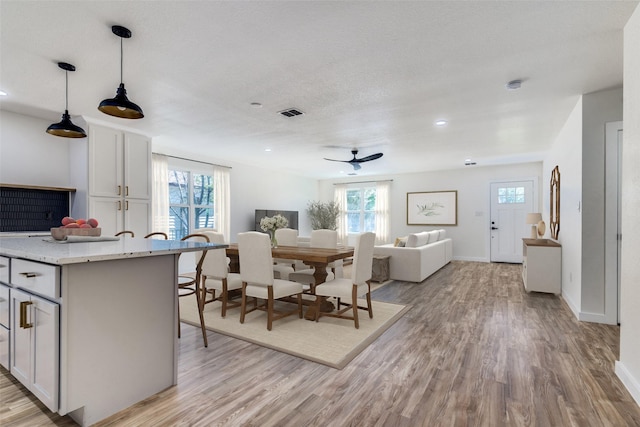 dining area with ceiling fan, light hardwood / wood-style flooring, and a textured ceiling