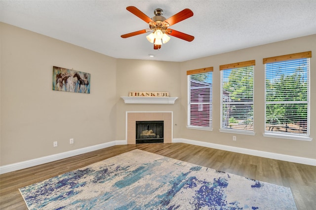 unfurnished living room featuring hardwood / wood-style flooring, ceiling fan, a fireplace, and a textured ceiling