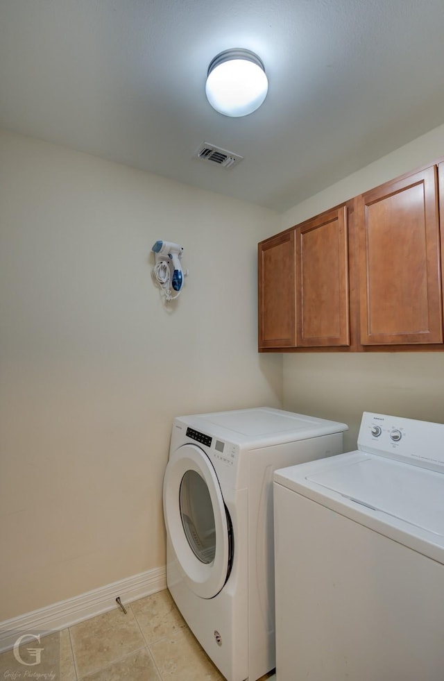 laundry area with cabinets, light tile patterned floors, and washer and dryer