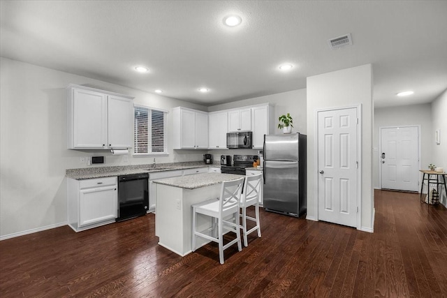 kitchen featuring white cabinets, a center island, a breakfast bar area, and black appliances