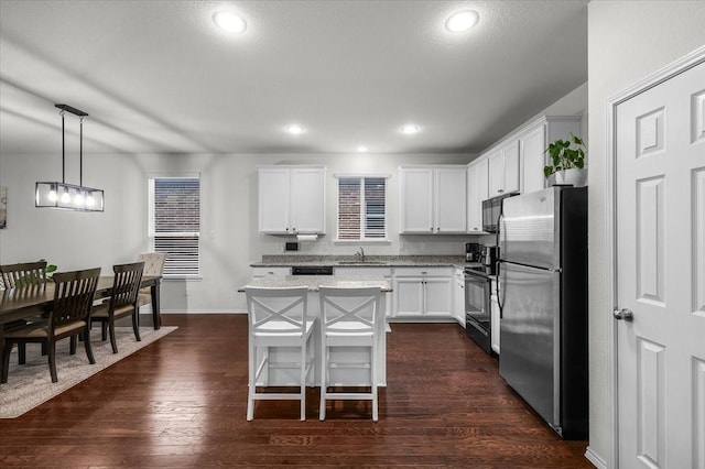 kitchen with sink, a center island, black appliances, white cabinets, and decorative light fixtures