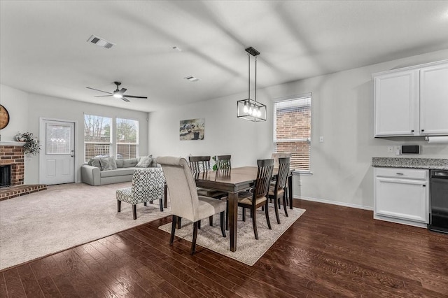 dining area with ceiling fan, a fireplace, and dark hardwood / wood-style flooring