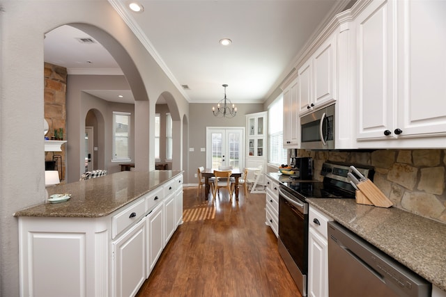 kitchen featuring dark hardwood / wood-style floors, pendant lighting, white cabinetry, light stone counters, and stainless steel appliances