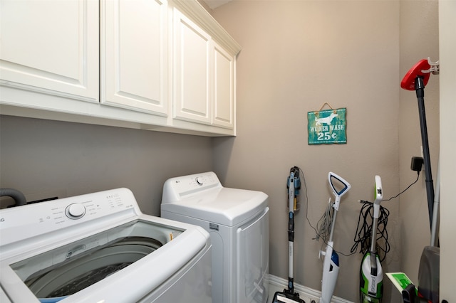 clothes washing area with cabinets and washer and clothes dryer