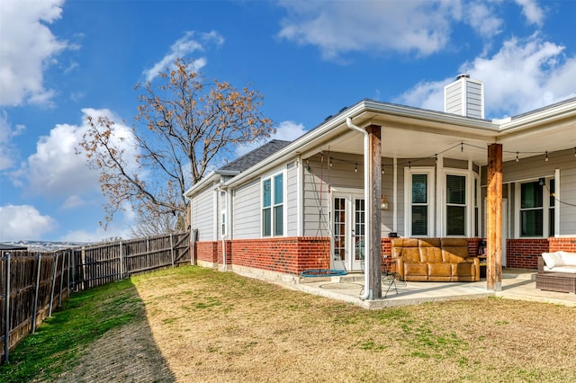 back of house featuring french doors, a patio, and a lawn