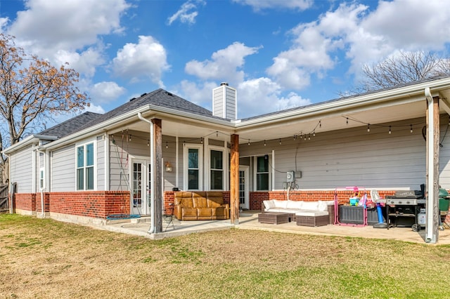 rear view of property featuring an outdoor hangout area, a patio area, and a lawn