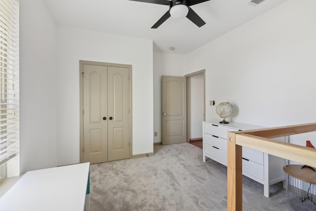 bedroom with ceiling fan, light colored carpet, and a closet