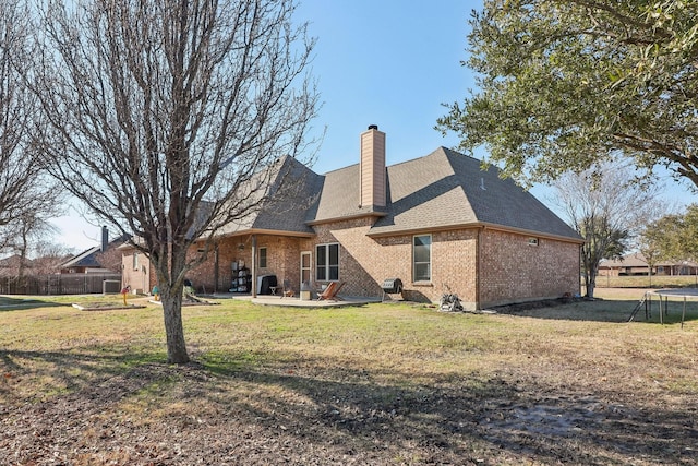 back of property with brick siding, fence, a chimney, a yard, and a patio