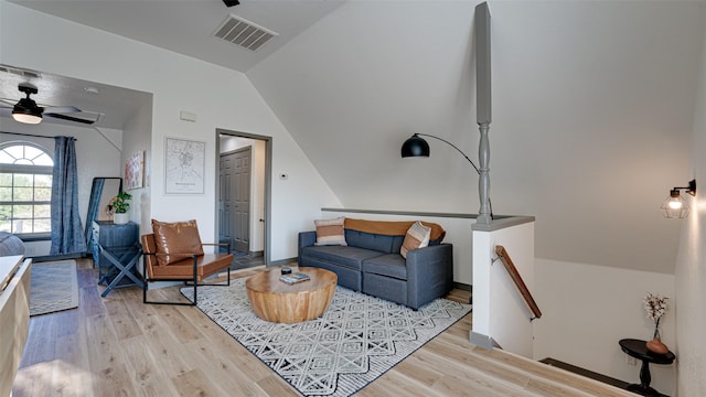 living area with light wood-type flooring, visible vents, a ceiling fan, and vaulted ceiling