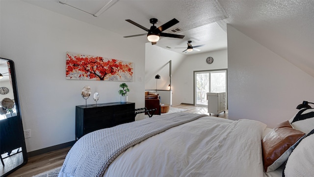 bedroom with visible vents, baseboards, vaulted ceiling, wood finished floors, and a textured ceiling