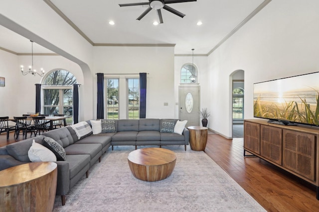 living room featuring ceiling fan with notable chandelier, wood finished floors, and ornamental molding