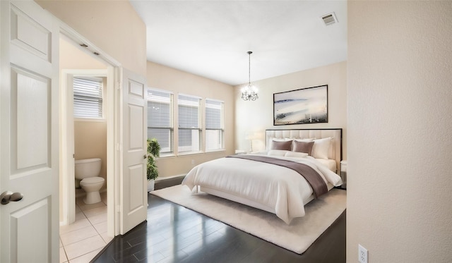 bedroom featuring an inviting chandelier, dark hardwood / wood-style floors, connected bathroom, and multiple windows