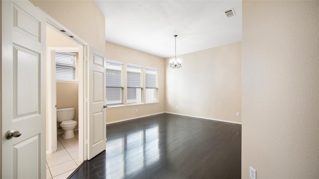 empty room featuring dark hardwood / wood-style floors and a notable chandelier