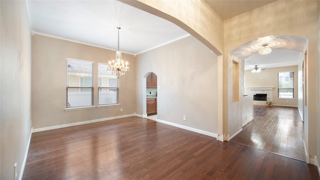 empty room with dark hardwood / wood-style flooring, ceiling fan with notable chandelier, and crown molding