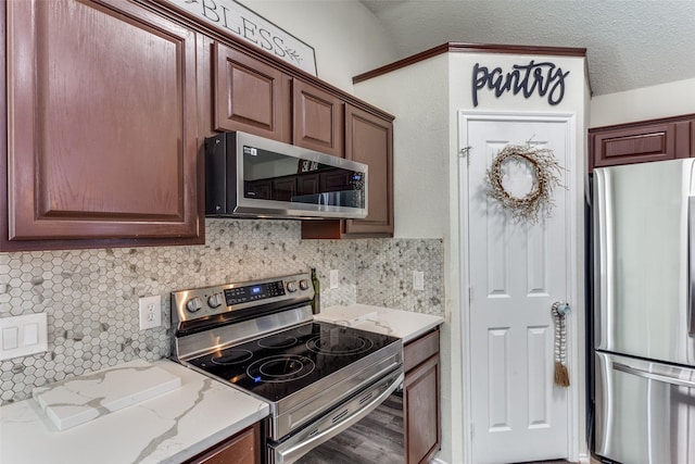 kitchen with light stone counters, decorative backsplash, stainless steel appliances, and a textured ceiling