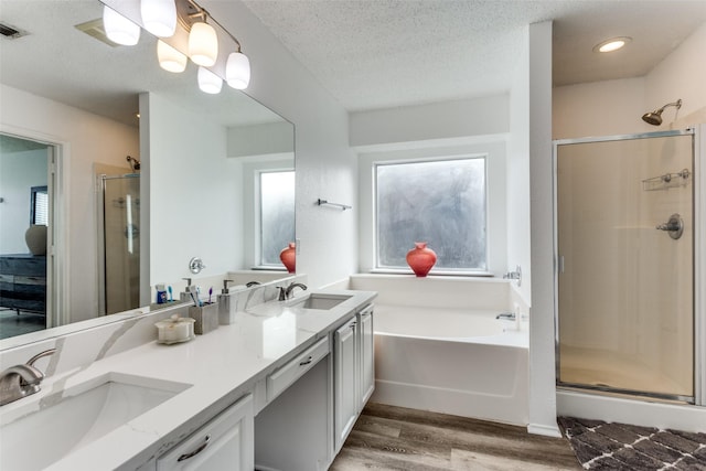 bathroom featuring wood-type flooring, separate shower and tub, vanity, and a textured ceiling