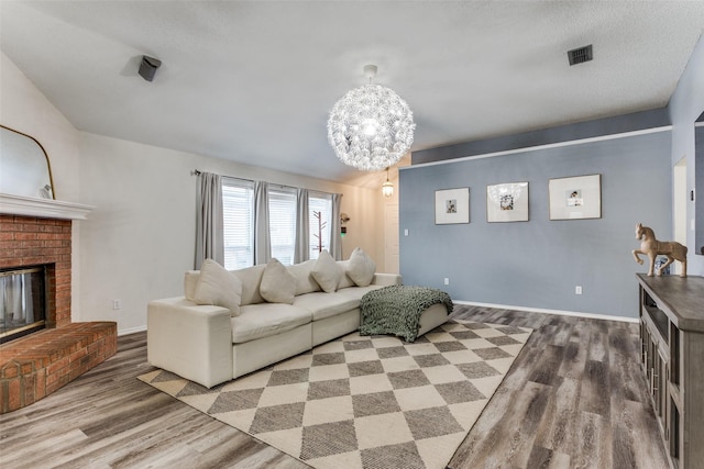 living room with hardwood / wood-style floors, a chandelier, and a brick fireplace