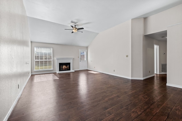 unfurnished living room featuring vaulted ceiling, a brick fireplace, dark wood-type flooring, and ceiling fan