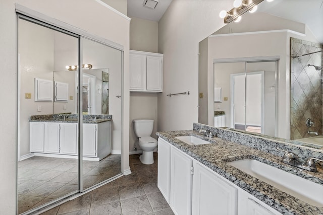 bathroom featuring tile patterned flooring, vanity, tiled shower, and toilet