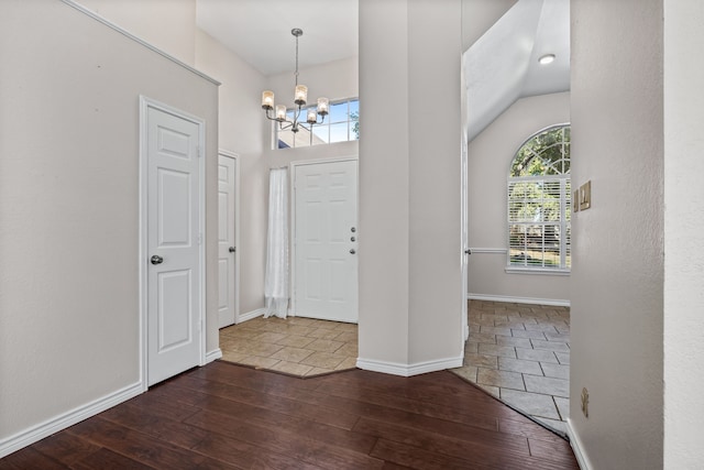 entryway with a notable chandelier, high vaulted ceiling, and dark hardwood / wood-style floors