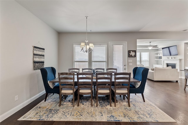 dining space featuring dark wood-type flooring and ceiling fan with notable chandelier