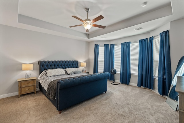 carpeted bedroom with ceiling fan and a tray ceiling