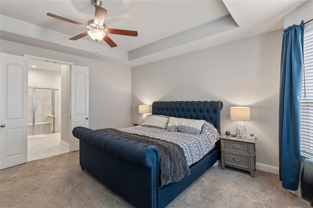 carpeted bedroom with ensuite bath, a raised ceiling, and ceiling fan