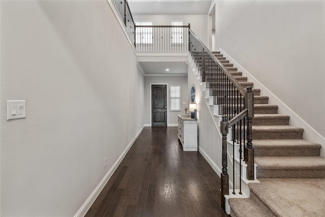 stairway featuring hardwood / wood-style flooring, ornamental molding, and a high ceiling