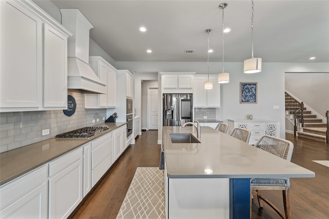 kitchen with sink, a breakfast bar area, a center island with sink, pendant lighting, and stainless steel appliances