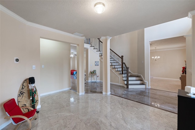 foyer entrance with decorative columns, crown molding, an inviting chandelier, and a textured ceiling