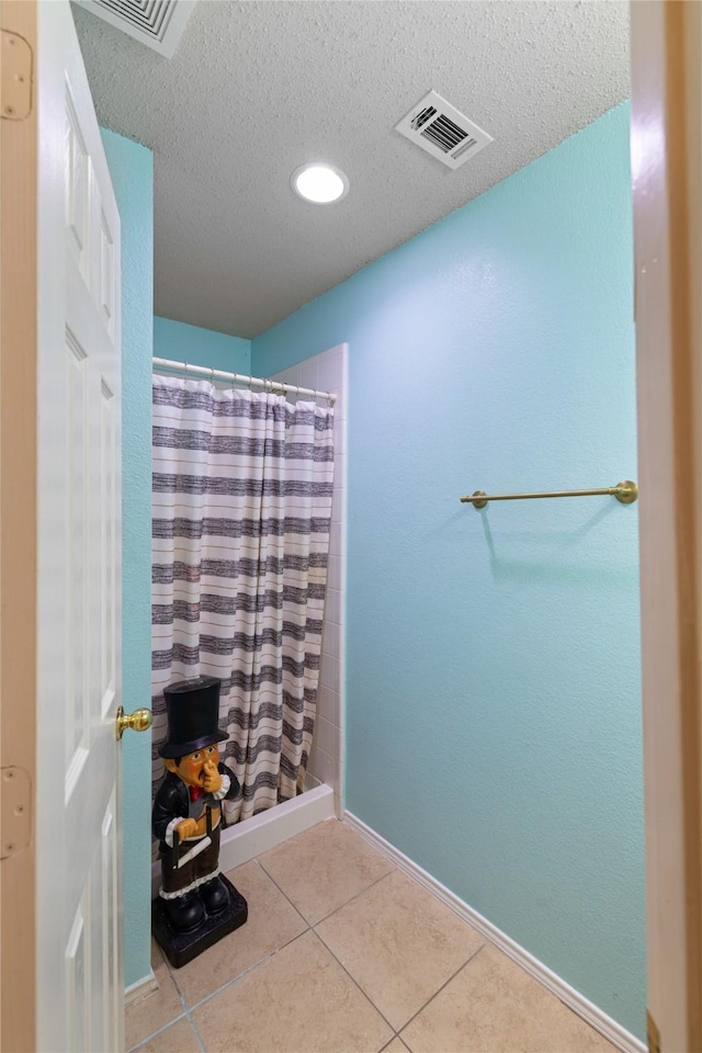 bathroom with a shower with shower curtain, tile patterned flooring, and a textured ceiling