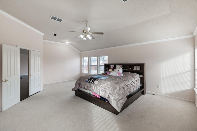 carpeted bedroom with crown molding, vaulted ceiling, a closet, and ceiling fan