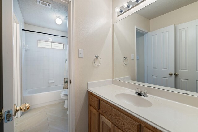 full bathroom with tile patterned flooring, vanity, a textured ceiling, toilet, and tiled shower / bath