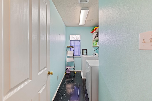 laundry area with dark tile patterned floors, independent washer and dryer, and a textured ceiling