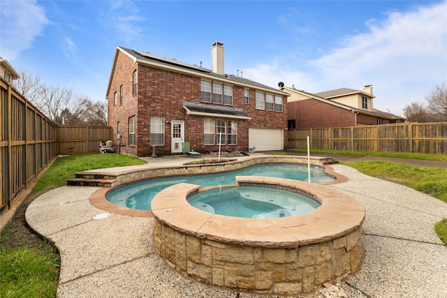 back of property with a swimming pool with hot tub, a garage, and a patio