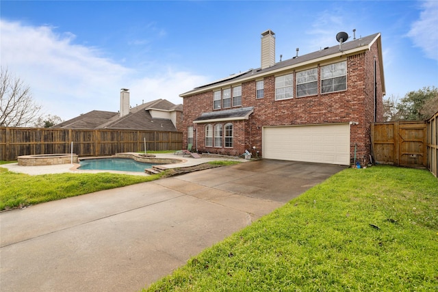 back of property with a yard, a garage, and a fenced in pool